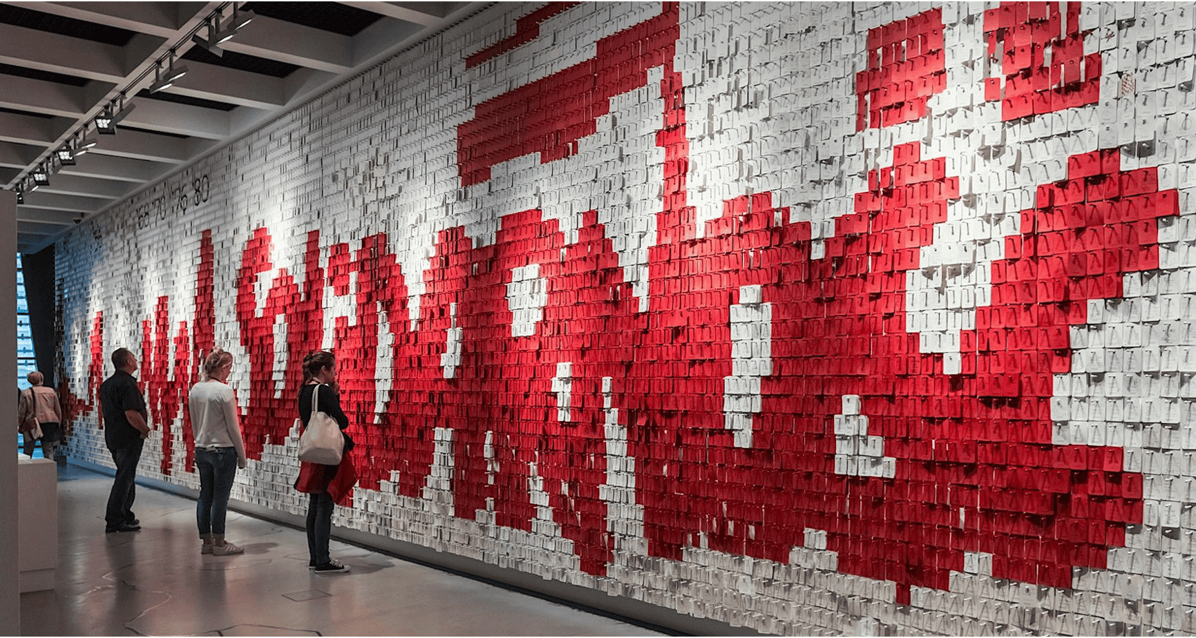 Visitors viewing a Solidarnosc installation, the Solidarity logo spelled out in red blocks across a gallery wall